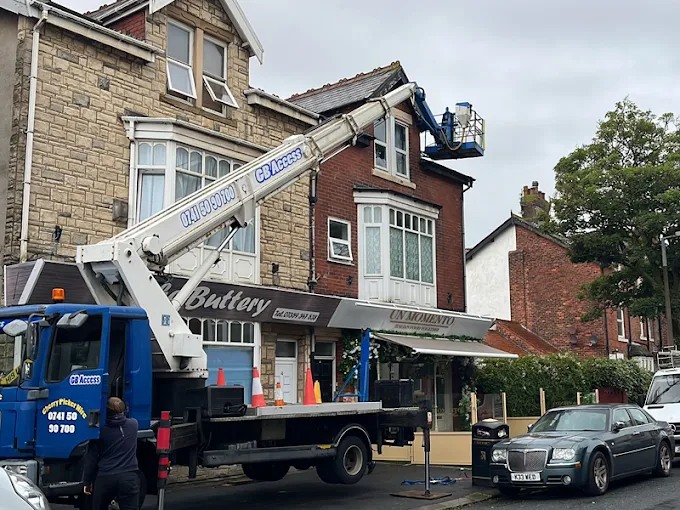 A cherry picker platform raised from a truck in the road, reaching the roof above the Un Momento restaurant.