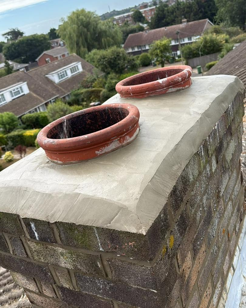 Brick chimney with terracotta pots and renewed mortar around the top