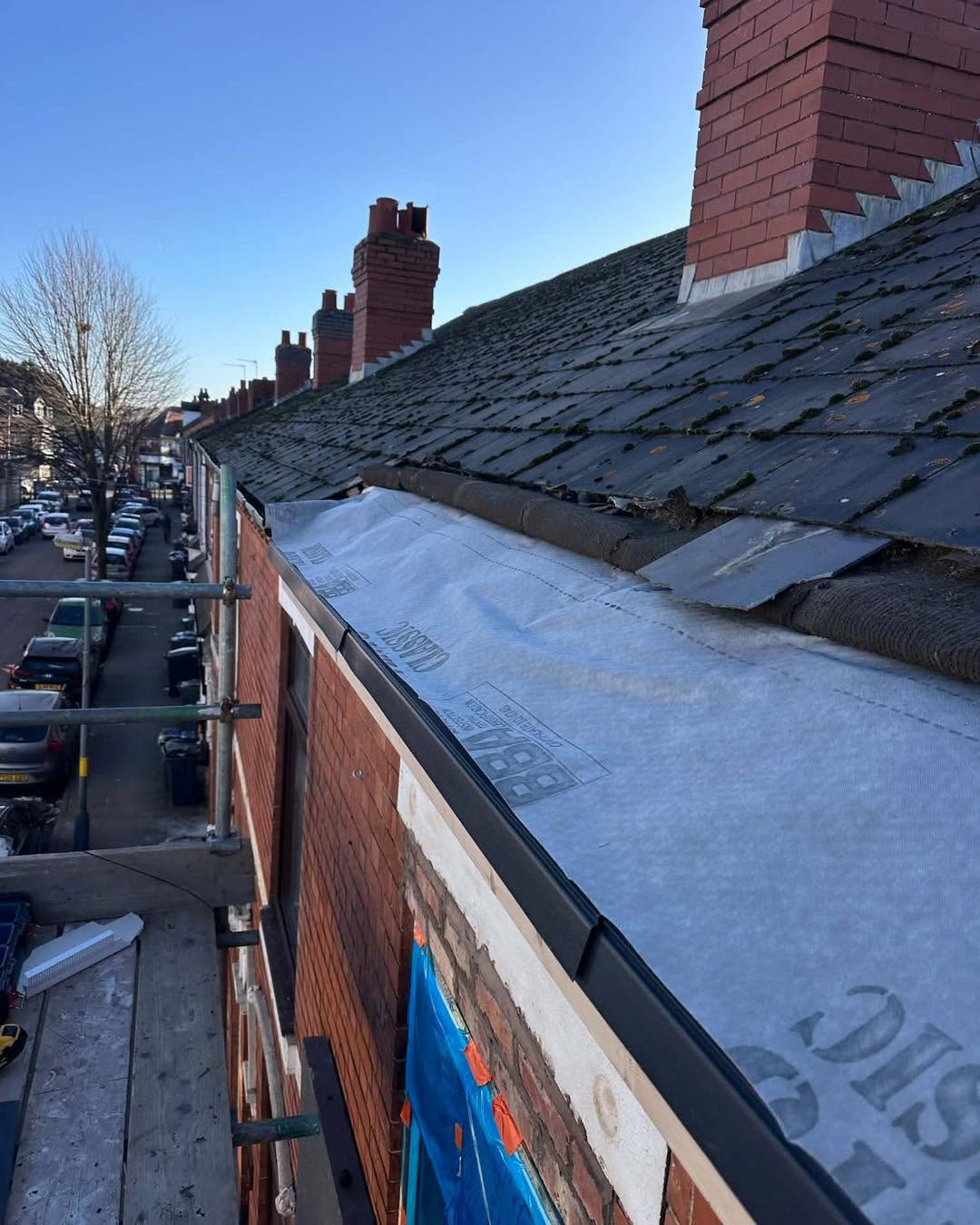 Roofline and guttering work along a brick terraced house